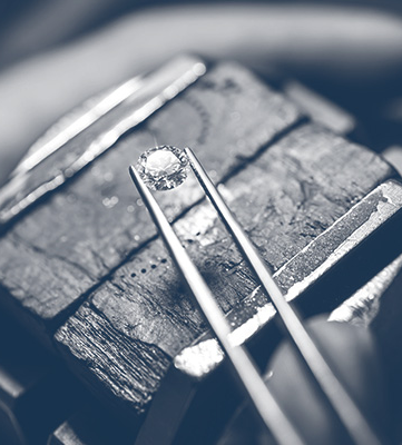 A diamond held in tweezers during inspection