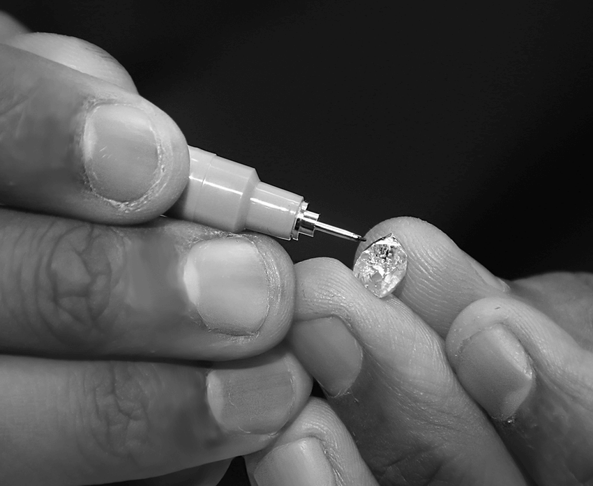 Close view of hands examining a rough diamond